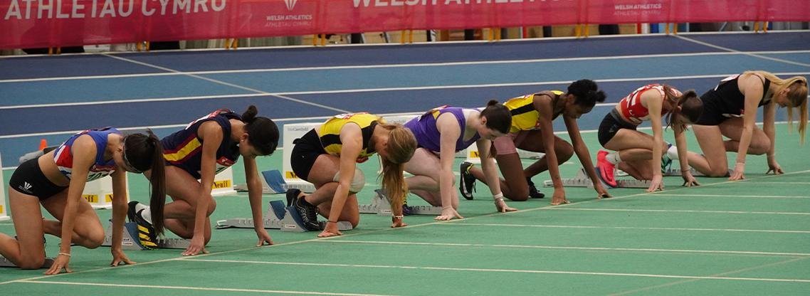 Junior girls athletes lining up at the start of a race.